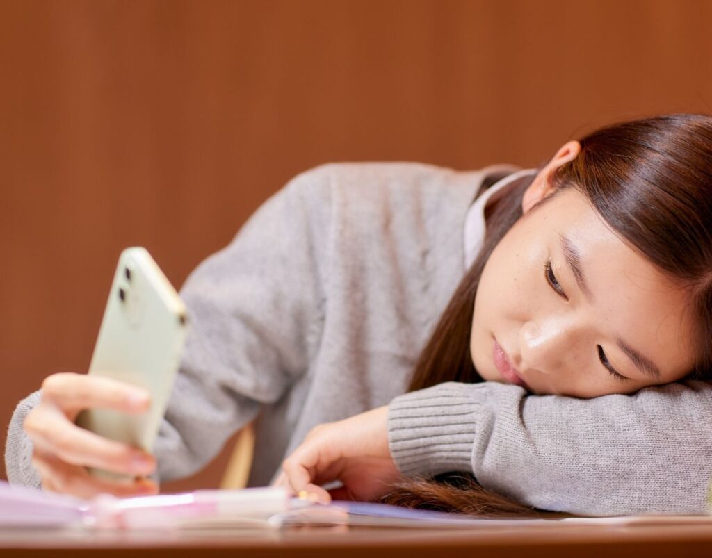 Une jeune fille asiatique regarde son téléphone d'un air triste